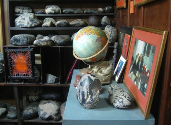 La oficina del museo con escritorio con
                            globo con repisa con piedras al fondo